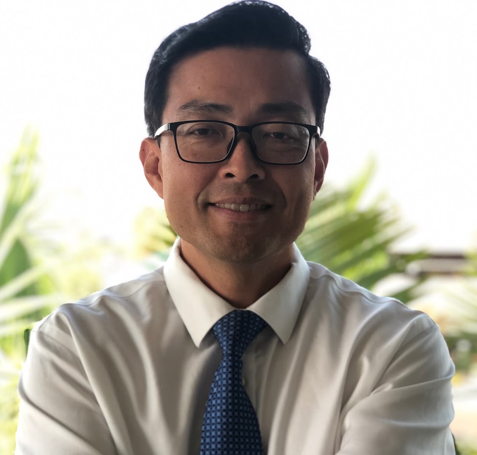 Portrait of Dr. Timothy Chiu, smiling, in a white shirt and blue tie